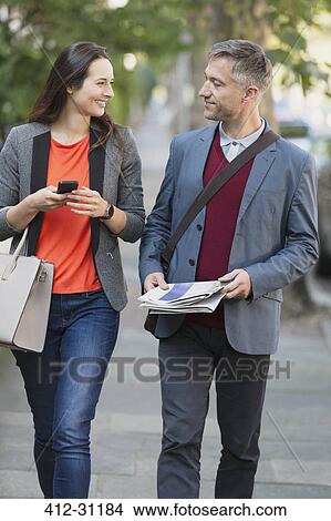 Picture - Business couple walking and talking on sidewalk. Fotosearch