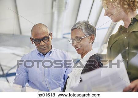 Stock Photo - Business people discussing paperwork in meeting. Fotosearch