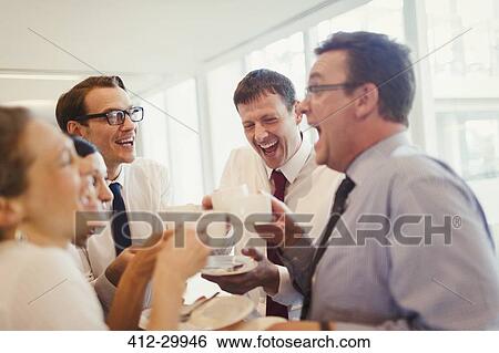 Stock Photograph - Business people laughing and drinking coffee in office. Fotosearch