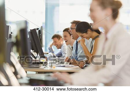 Picture - Business people laughing at desk in office. Fotosearch
