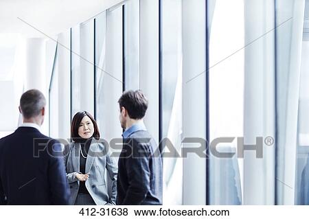 Business people talking at office window View Large Photo Image Stock Photo - Business people talking at office window. Fotosearch