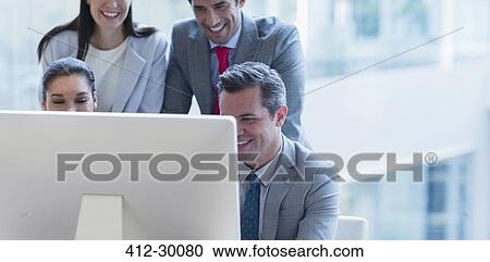Stock Image - Business people working at computer in sunny office. Fotosearch