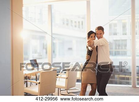 Stock Photograph - Businessman and businesswoman dancing in conference room. Fotosearch