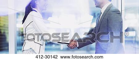 Stock Image - Businessman and businesswoman handshaking in office. Fotosearch