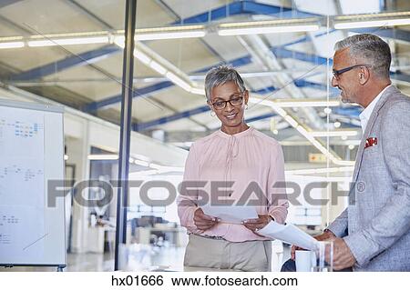 Stock Photograph - Businessman and businesswoman discussing paperwork. Fotosearch