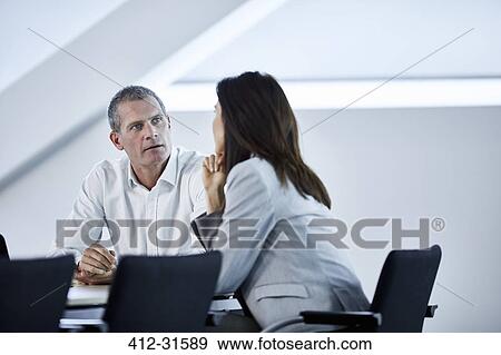 Stock Photo - Businessman and businesswoman talking in meeting. Fotosearch