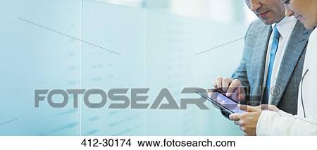 Businessman and businesswoman using digital tablet in office corridor View Large Photo Image Picture - Businessman and businesswoman using digital tablet in office corridor. Fotosearch