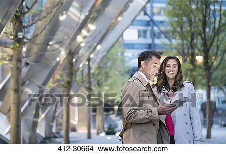 Businessman and businesswoman using digital tablet in courtyard View Large Photo Image Picture - Businessman and businesswoman using digital tablet in courtyard. Fotosearch