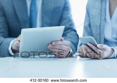 Stock Image - Businessman and businesswoman using digital tablet and cell phone. Fotosearch