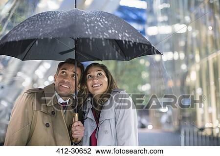 Businessman and businesswoman watching rain under umbrella View Large Photo Image Stock Image - Businessman and businesswoman watching rain under umbrella. Fotosearch