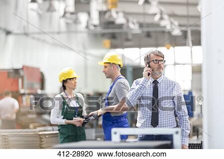 Businessman and workers in factory View Large Photo Image Stock Image - Businessman and workers in factory. Fotosearch