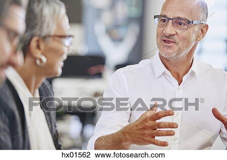 Businessman explaining to colleagues in meeting View Large Photo Image Stock Image - Businessman explaining to colleagues in meeting. Fotosearch