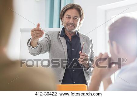 Businessman gesturing and leading meeting in office View Large Photo Image Stock Image - Businessman gesturing and leading meeting in office. Fotosearch