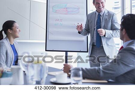 Businessman leading meeting at whiteboard flip chart in conference room View Large Photo Image Stock Photo - Businessman leading meeting at whiteboard flip chart in conference room. Fotosearch
