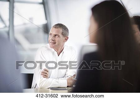 Stock Image - Businessman listening looking away in meeting. Fotosearch