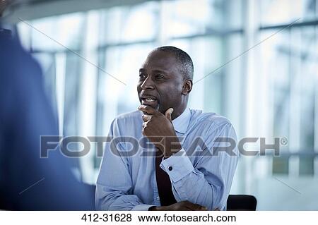 Stock Photo - Businessman listening looking away in meeting. Fotosearch