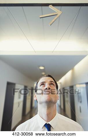 Businessman looking up at arrow overhead View Large Photo Image Stock Photo - Businessman looking up at arrow overhead. Fotosearch