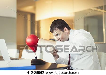 Businessman punching toy punching bag in office View Large Photo Image Stock Image - Businessman punching toy punching bag in office. Fotosearch