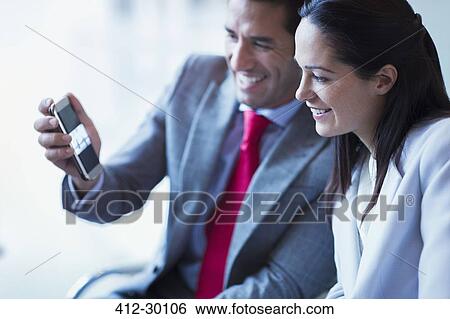 Businessman showing cell phone video to businesswoman View Large Photo Image Stock Photograph - Businessman showing cell phone video to businesswoman. Fotosearch