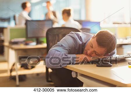 Stock Photography - Businessman sleeping on desk in office. Fotosearch