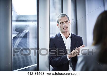 Businessman talking to businesswoman in office View Large Photo Image Stock Photo - Businessman talking to businesswoman in office. Fotosearch