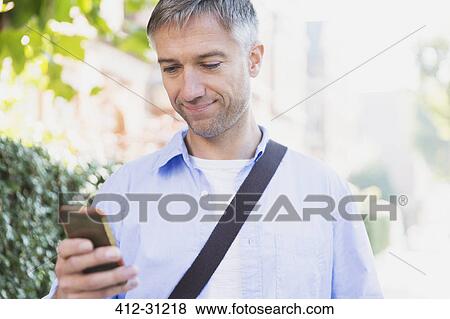 Stock Photo - Businessman texting with cell phone outdoors. Fotosearch