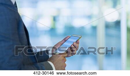 Stock Photograph - Businessman using cell phone in office. Fotosearch