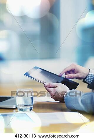 Stock Image - Businessman using digital tablet at conference table. Fotosearch