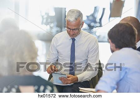 Businessman using digital tablet in meeting View Large Photo Image Stock Image - Businessman using digital tablet in meeting. Fotosearch