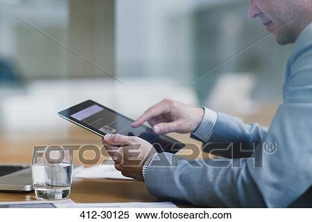 Stock Photography - Businessman using digital tablet in office. Fotosearch