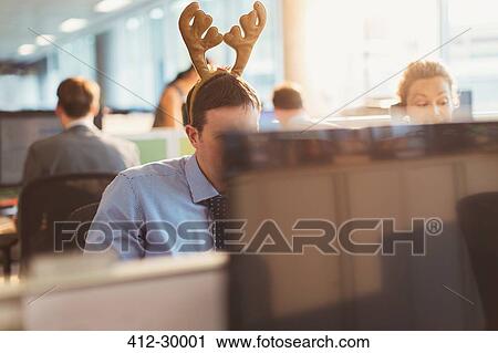 Businessman wearing antler headband in office View Large Photo Image Stock Image - Businessman wearing antler headband in office. Fotosearch