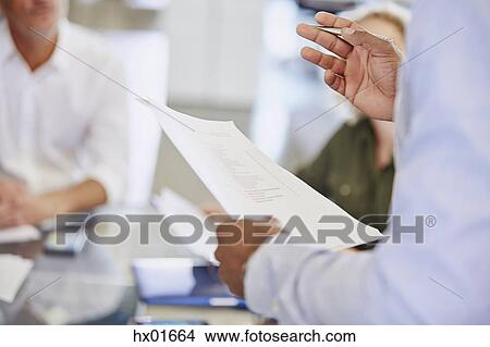 Businessman with paperwork gesturing in meeting View Large Photo Image Picture - Businessman with paperwork gesturing in meeting. Fotosearch