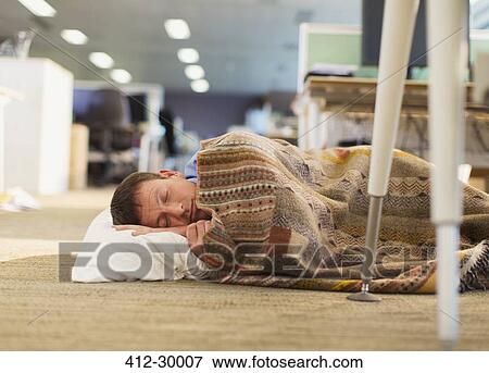 Stock Photo - Businessman with pillow and blanket sleeping on office floor. Fotosearch