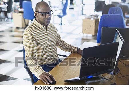 Businessman working at laptop and computer in office View Large Photo Image Stock Image - Businessman working at laptop and computer in office. Fotosearch