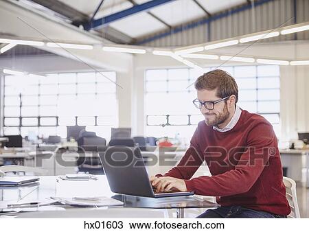 Stock Image - Businessman working at laptop in office. Fotosearch