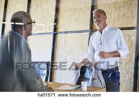 Stock Image - Businessmen talking in conference room meeting. Fotosearch