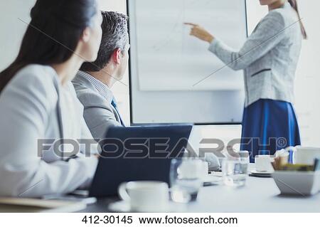 Stock Photography - Businesswoman leading meeting at flip chart in conference room. Fotosearch