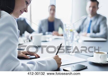 Businesswoman reviewing paperwork in conference room meeting View Large Photo Image Stock Image - Businesswoman reviewing paperwork in conference room meeting. Fotosearch