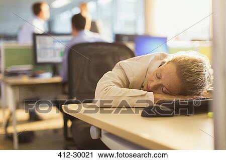 Stock Image - Businesswoman sleeping on desk in office. Fotosearch