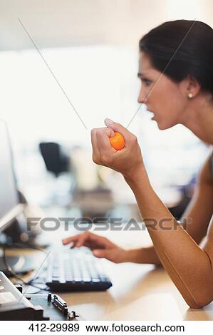 Businesswoman squeezing stress ball at computer in office View Large Photo Image Stock Photo - Businesswoman squeezing stress ball at computer in office. Fotosearch