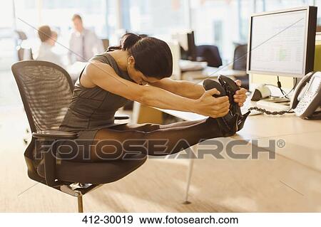 Stock Photo - Businesswoman stretching legs with feet up on desk in office. Fotosearch