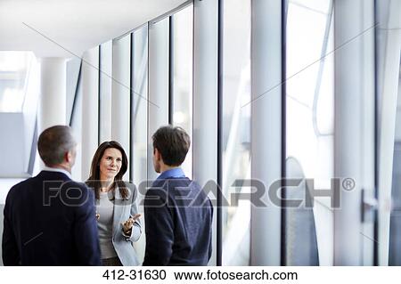 Businesswoman talking to businessmen at office window View Large Photo Image Stock Image - Businesswoman talking to businessmen at office window. Fotosearch