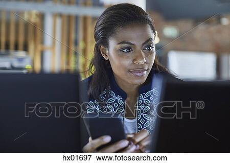 Businesswoman texting at computer in office View Large Photo Image Stock Photo - Businesswoman texting at computer in office. Fotosearch