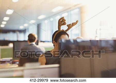 Stock Photo - Businesswoman wearing antler headband in office. Fotosearch