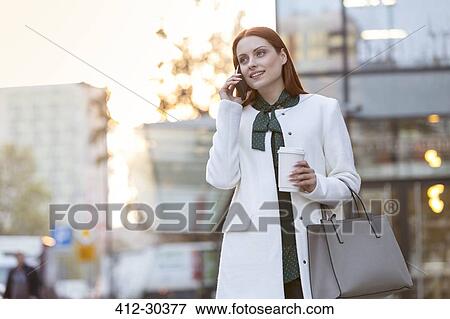 Businesswoman with coffee talking on cell phone in city View Large Photo Image Stock Photo - Businesswoman with coffee talking on cell phone in city. Fotosearch