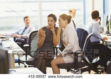 Stock Photo - Businesswomen gossiping in office. Fotosearch