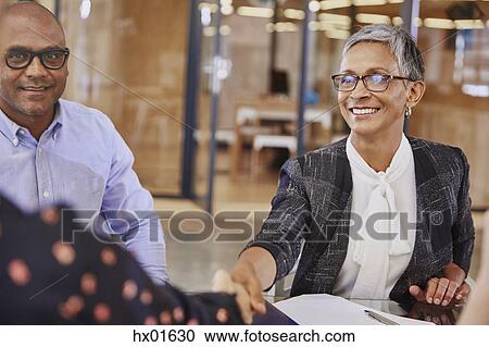 Stock Image - Businesswomen handshaking in meeting. Fotosearch