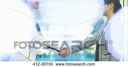 Stock Photography - Businesswomen handshaking in office. Fotosearch