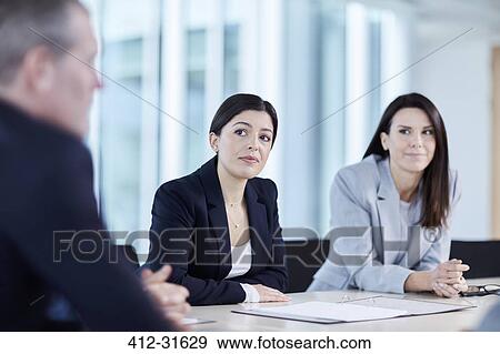 Businesswomen listening to colleague in meeting View Large Photo Image Stock Photo - Businesswomen listening to colleague in meeting. Fotosearch