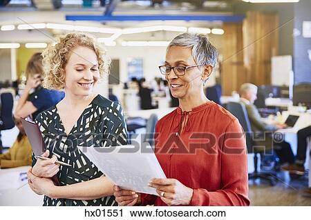 Businesswomen reviewing paperwork in office View Large Photo Image Stock Image - Businesswomen reviewing paperwork in office. Fotosearch
